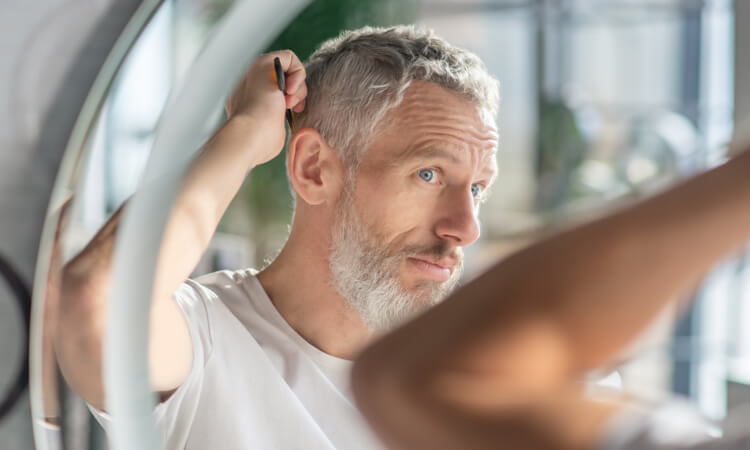 A middle age man combing his hair. It is important to have a valid guarantee for your hair transplant